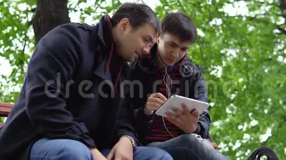 两个年轻人在公园里用平板电脑视频的预览图