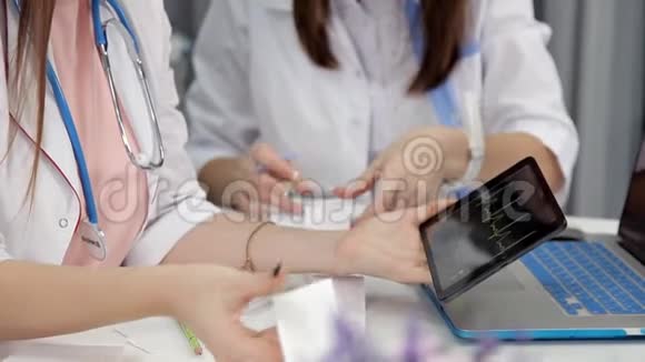女医生拿着笔记本电脑和平板电脑在办公室的桌子上工作视频的预览图