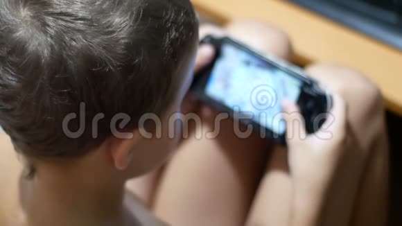8岁的孩子在家里坐在椅子上的便携式游戏机上玩电子游戏视频的预览图