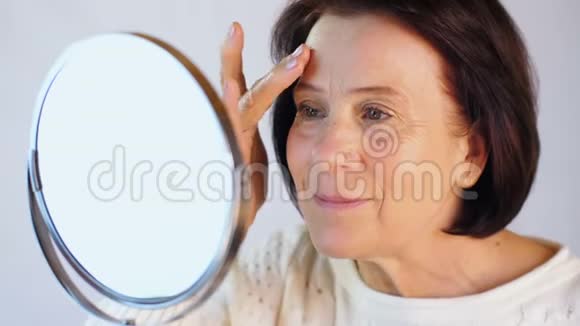 老年妇女抚摸着脸上的皮肤视频的预览图