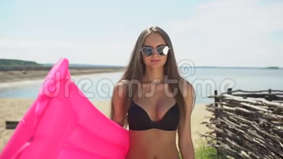 美丽的年轻比基尼女人拿着粉红色的气垫比基尼女孩在夏天在热带放松的概念视频的预览图