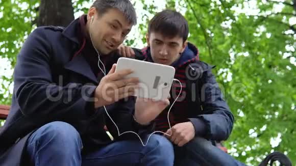 两个年轻人在公园里用平板电脑视频的预览图