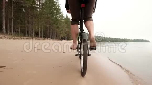 一个赤脚的人在海滩上骑自行车在湖边度假时放松一下视频的预览图