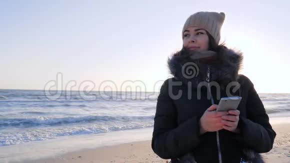 网络成瘾女孩用手机在阳光下在海堤聊天视频的预览图
