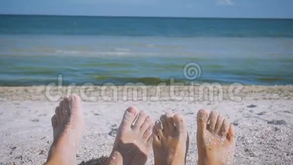 男人和女人脚在沙滩上靠在大海上嬉戏有趣地扭动手指恋爱中的情侣浪漫视频的预览图