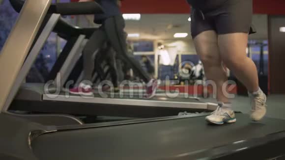 不健康的胖女人在跑步机上勉强行走努力减肥视频的预览图