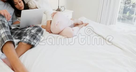 一对浪漫的情侣在床上用笔记本电脑视频的预览图