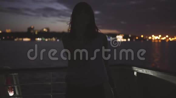 一个年轻迷人的女人在船上夜城背景下的剪影视频的预览图