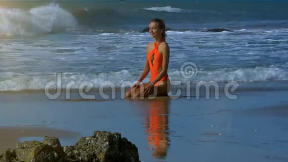 在海洋水线上穿橙色休闲裤的女孩视频的预览图