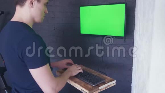 年轻人正在用一个绿色屏幕模拟电脑工作4键盘上快速打字视频的预览图