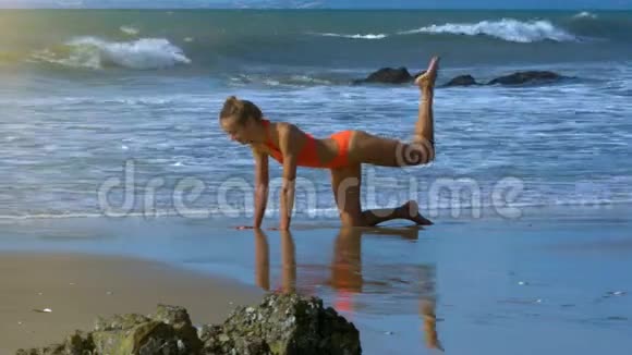 金发女孩站在膝盖上用泡沫波浪在海滩上锻炼视频的预览图