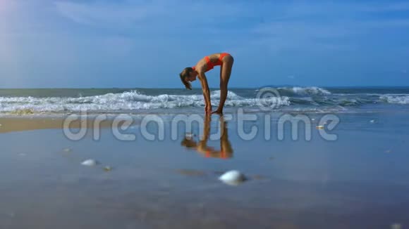 泳滩沙水中瑜伽姿势中的苗条女孩形象视频的预览图