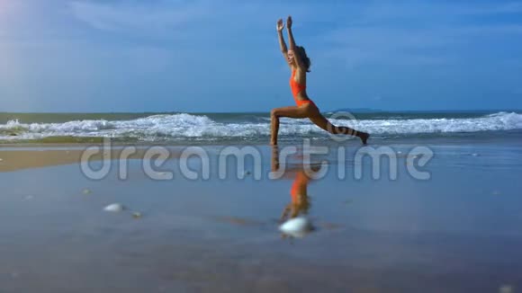 女人让瑜伽战士在靠近泡沫波浪的海滩上做姿势视频的预览图