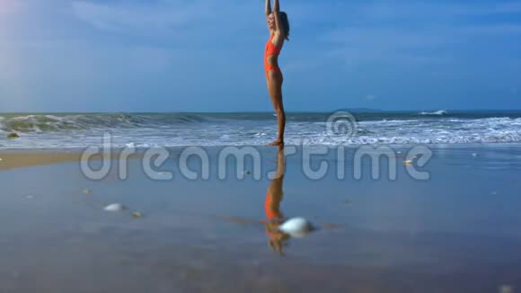 泳滩浅水区瑜伽位置的瘦长海女视频的预览图