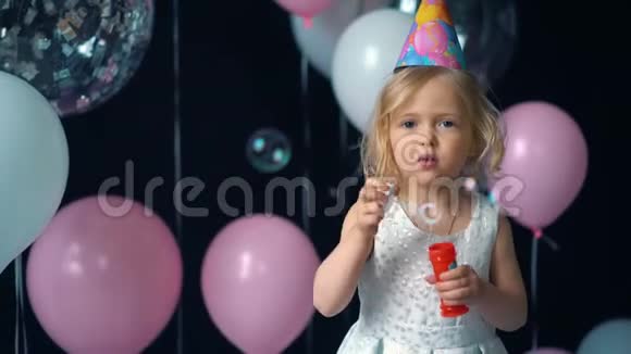 小女孩在节日里吹泡泡背景是气球和纸屑视频的预览图