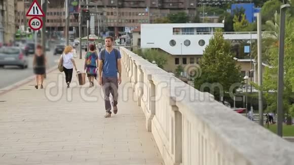年轻男子背着背包走过大桥看着城市地标视频的预览图