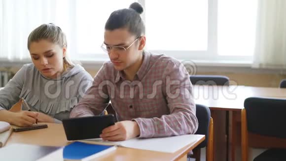 年轻的大学生们一起使用平板电脑讨论准备考试的项目坐在桌旁视频的预览图