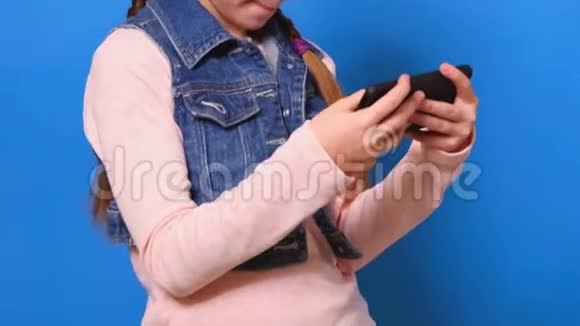 戴着耳机在智能手机上玩电子游戏的小可爱女孩视频的预览图