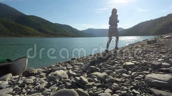 阳光明媚的一天年轻女子沿着阳光充足的沙滩在山上慢跑视频的预览图