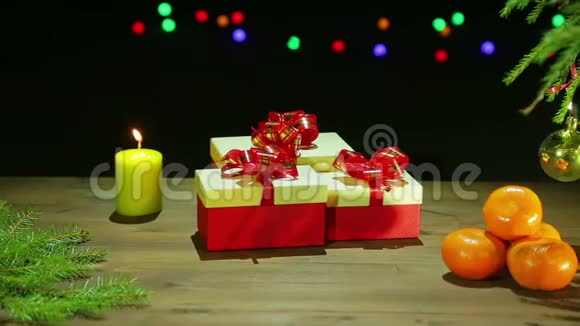 漂亮的盒子旁边是圣诞树和一支燃烧的蜡烛黑色背景上有灯视频的预览图