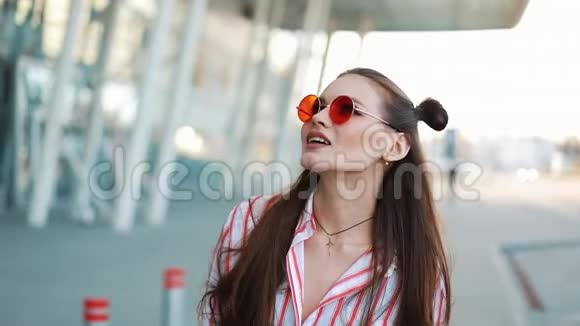 时尚模特戴着红色太阳镜自信地走在购物中心附近的街道上夏季视频的预览图