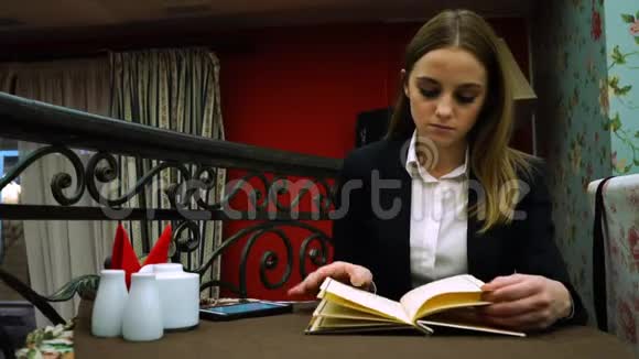 一个穿着夹克衫的年轻女孩在咖啡馆里检查菜单视频的预览图