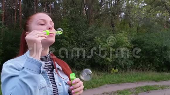 一个夏天的晚上年轻的女人在公园里吹泡泡视频的预览图