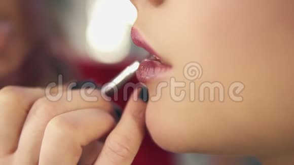 一位专业化妆师用特殊的刷子在模特的嘴唇上涂口红这是她的特写镜头视频的预览图