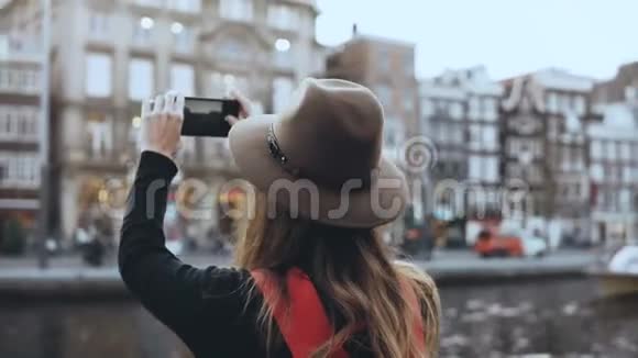 旅游女士拍摄旧建筑的照片长发和红色背包的女孩享受着令人惊叹的城市风景4K视频的预览图