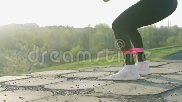 日落时做体操的小可爱女孩运动员用健身橡皮筋做运动视频的预览图