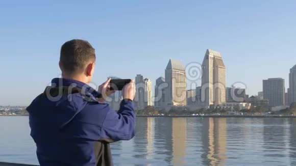 游客正在用智能手机拍摄圣地亚哥黎明的照片视频的预览图