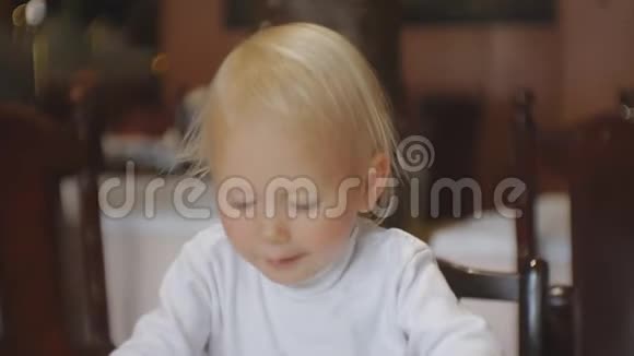 婴儿在餐馆吃食物金发碧眼的孩子在高椅上给盘子后吃视频的预览图