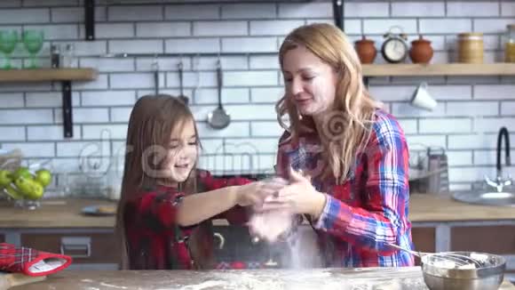 无忧无虑可爱的年轻母女在厨房里胡闹妈妈和孩子一起玩得很开心视频的预览图