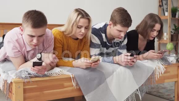 一群沉迷于网络的电话用户躺在床上看着智能手机视频的预览图