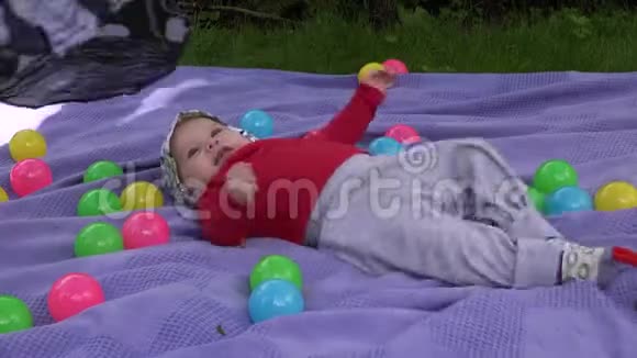 小女孩笑踢腿躺在花园里的垫子上4K视频的预览图