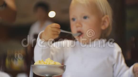 婴儿在餐馆吃食物金发碧眼的孩子坐在高椅上吃冰淇淋而服务员带来了一道新菜视频的预览图