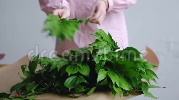 女花匠在牛皮纸上为一束花整理绿色视频的预览图