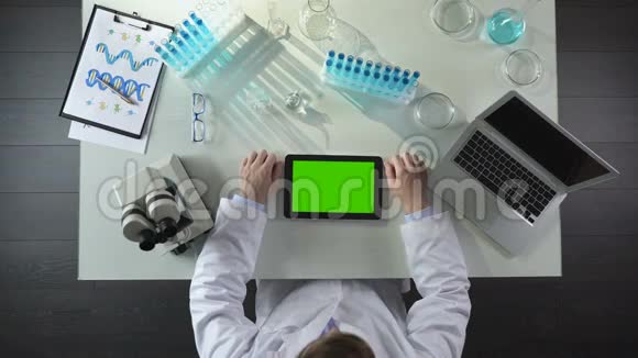 实验室工作人员带绿色屏幕滚动平板电脑的俯视图现代实验室视频的预览图