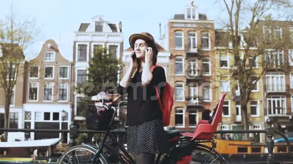 骑自行车的快乐欧洲女士在电话里交谈美丽的女游客和一个朋友愉快地微笑着交谈4K视频的预览图
