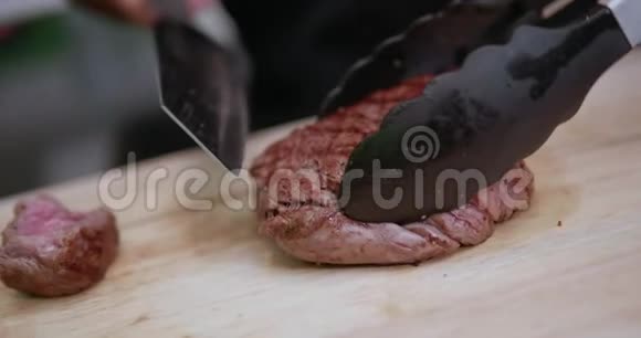 用锋利的刀在木切割板上切下烤鲑鱼片视频的预览图
