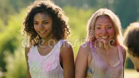朋友们在两个兴奋的年轻女子身上泼水身上沾满了彩色粉末视频的预览图