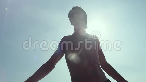 在阳光和蓝天的映衬下年轻英俊的男子站在开放的小游船上视频的预览图