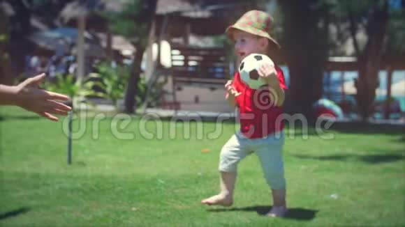 可爱的小男孩玩着一个足球拥抱着他的母亲库存录像视频的预览图