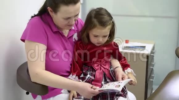 小女孩和牙医医生看贴有贴纸的书视频的预览图