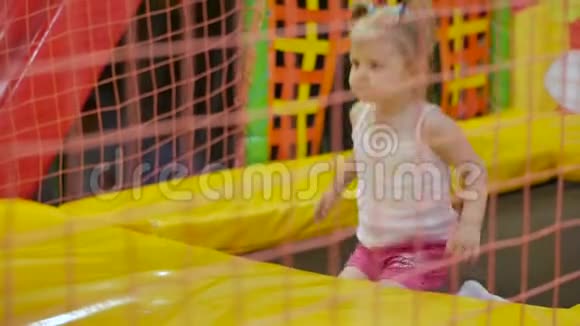 小女孩跳上一个色彩鲜艳的室内蹦床视频的预览图