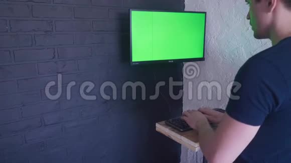 年轻人正在用一个绿色屏幕模拟电脑工作4键盘上快速打字视频的预览图