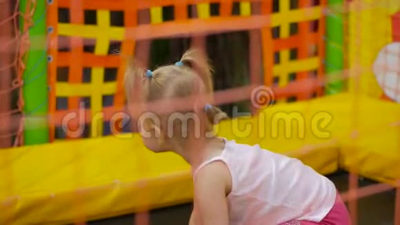 小女孩跳上一个色彩鲜艳的室内蹦床视频的预览图