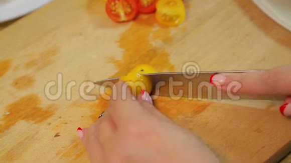 一个女人正在用一把刀在木板上切一个黄色和红色的樱桃番茄视频的预览图
