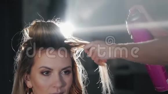 一个金发女孩把头发绕到理发店一个发型师给一个卷发的女人做发型视频的预览图