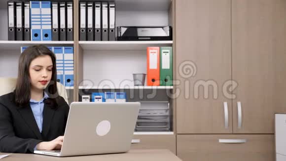 办公室里的年轻女商人在电脑上打字然后接电话视频的预览图